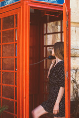 Young woman in telephone cabin talking on the phone