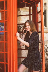 Young woman in telephone cabin talking on the phone and smiling