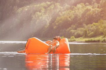 Man sleeping inside inflatable lounger in water.