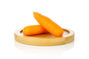 Group of two whole peeled orange baby cut carrot on bamboo plate isolated on white background