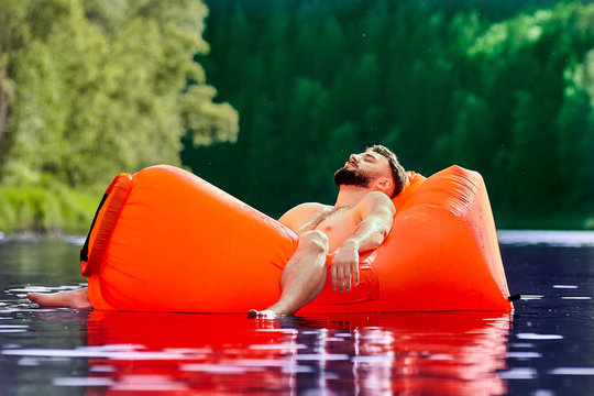 Tourist sleeping inside air sofa in water.