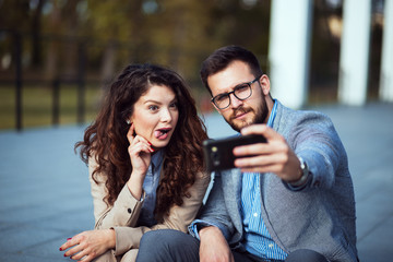 Business couple taking a funny crazy selfie with smartphone