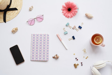 Female designers background with creative diary, clippers, cup of lemon tea, headphones, flower