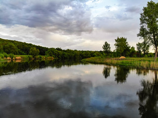 Peaceful landscape with green trees on river bank in evening