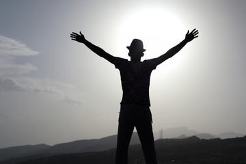 Fototapeta na wymiar Freedom and travel A man raises his hands with a mountain background