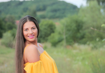 Young beautiful woman in yellow dress enjoying outside in park , on green summer background.