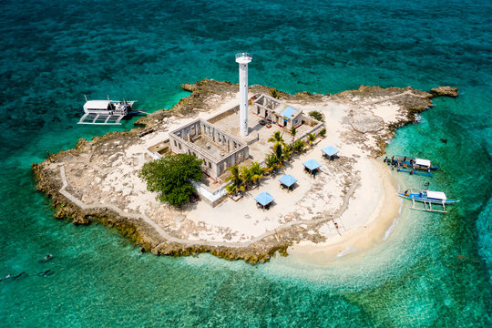 Aerial view of a tiny tropical island with a lighthouse surrounded by a huge coral reef (Capitancillo Island, Philippines)