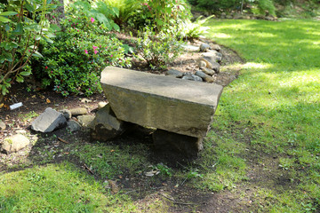 Stone bench in lush green park