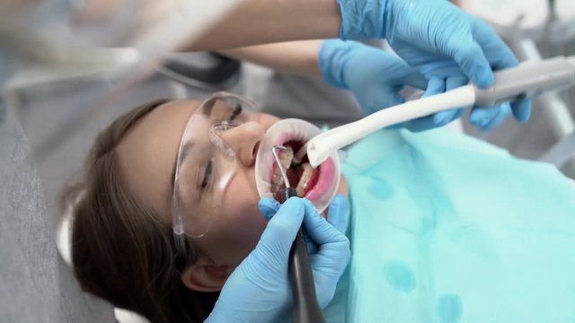 Pretty woman's teeth cleaning in dental clinic