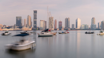 Fototapeta na wymiar Jersey City skyscrapers from hudson river yacht club at sunrise with long exposure