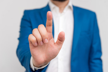 Businessman in blue suite and white shirt pointing with finger in empty space.