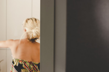 unfocused incognito girl in dress back to camera preparing to take a shower, white and gray background bath room soft focus interior with empty space for copy or text 
