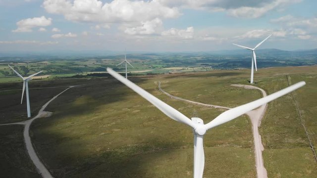 A descending shot of the Wind Turbines on Caton Moor. You can see the stunning green countryside on a sunny yet cloudy Summers day.