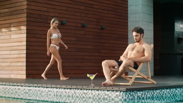 Busy man sitting with mobile near pool at private villa.