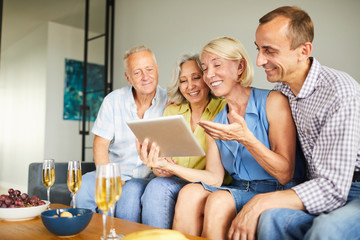 Group of contemporary adult people using digital tablet sitting on sofa at home, copy space