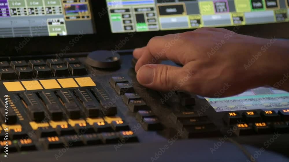 Poster hands using a control panel in a control room, during a live event. close up.