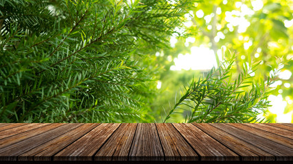 Brown grunge wood table with green leaves for product placement or editing your product or design elements. Wooden board empty table perspective.