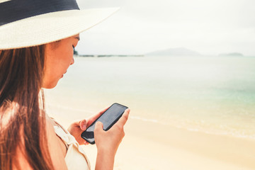 Asian women relaxing in summer using smart phone in holiday on beach