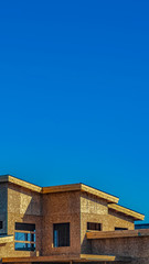 Vertical tall Exterior of a house under construction against vast blue sky on a sunny day