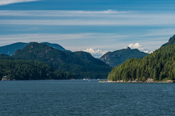 layers of forest covered mountains on the island over the horizon of the ocean under cloudy blue sky