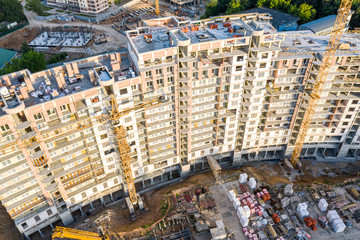 construction of new multistory apartment building. yellow tower cranes at construction site. aerial view