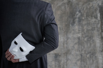 Businessman holding white mask in his hand dishonest cheating agreement.Faking and betray business...