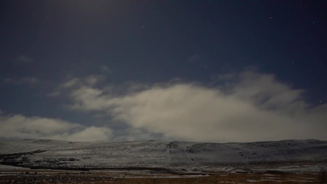 Night timelapses showing clouds moving in the wind with stars and weak northern lights in background.