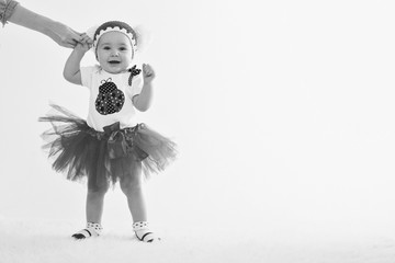 Cute baby learning to walk and make his first steps. mom is holding his hand. child's feet close up, copy space