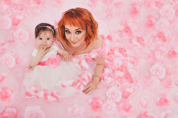 the child in the arms of his mother in a pink dress of flowers. A woman with a child in her arms on a white background, isolated