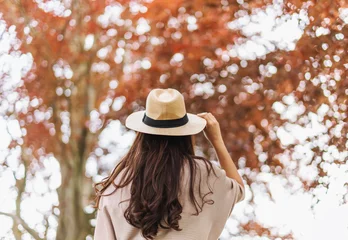 Fototapete Fotos Woman with hat looking at beautiful tree in autumn  © SasinParaksa