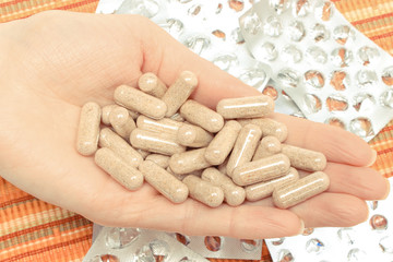 Medicine capsules in hand of woman and empty pills blisters