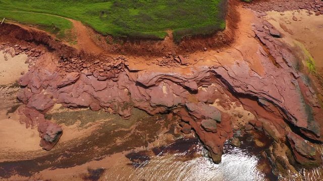 Sliding drone shot of Prince Edward Island north shore, with red sandstone cliffs, on a sunny day