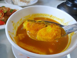 Thai food style,Selective focus of snapper fish on blurred sour soup and young coconut shoots in white bowl at restaurant ready to eat or served, This food is most popular
