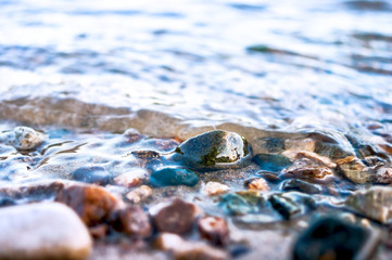 Close-up View of Colorful Pebbles in Water Waves. Travel Concept.