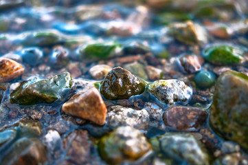 Close-up View of Colorful Pebbles in Water Waves. Travel Concept.