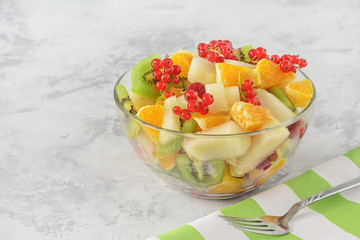 Fresh Snack Peeled Assorted Fruit Berry Salad Bowl. Low Calorie Healthy Breakfast Dish on Concrete Table. Ready to Eat Lunch. Ripe Orange, Kiwi Chopped Apple and Currant Cup Closeup