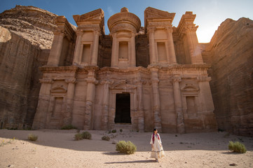 Asian woman tourist in white dress standing at Ad Deir or El Deir, the monument carved out of rock...
