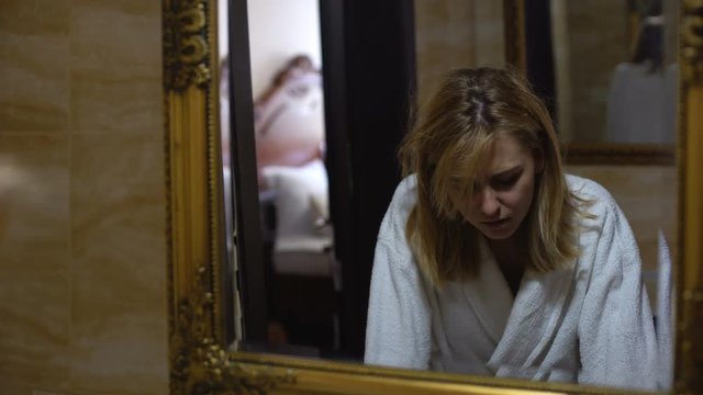 Young woman in bath robe feeling nausea after all-night party, morning hangover