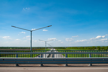 paved road and blue sky. The path goes into the distance. Landscape on a bright Sunny day,