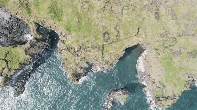 Majestic 4K bird's-eye view aerial of the turquoise North Atlantic ocean and seagulls flying next to the cliffs of Hellnar and Arnarstapi, both popular tourist attraction on the west coast of Iceland.