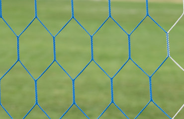 Fototapeta premium Soccer or football net background. Football net close up on blurred green grass football field 