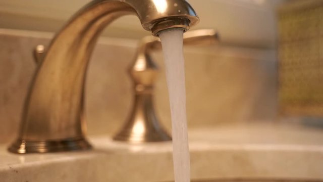 Slow motion turning off water from bathroom faucet right