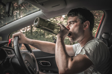 Drunk driver with bottle of wine driving a car