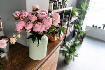 Fototapeta na wymiar The counter of the flower shop. Pink peonies in a metal vase. Beautiful peony flower for catalog or online store. Floral shop concept . Beautiful fresh cut bouquet. Flowers delivery
