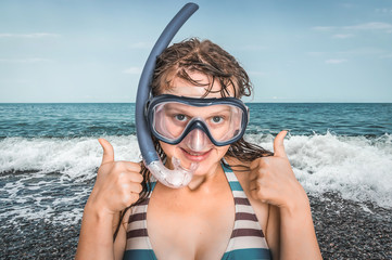 Woman with snorkeling mask for diving stands near the sea