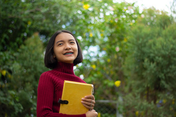 Happy young Asain girl hold notebook with green background.