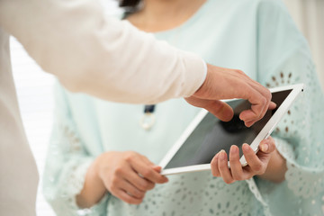 男性にタブレットPCを見せている女性