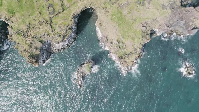 Majestic 4K bird's-eye view aerial of the turquoise North Atlantic ocean and seagulls flying next to the cliffs of Hellnar and Arnarstapi, both popular tourist attraction on the west coast of Iceland.