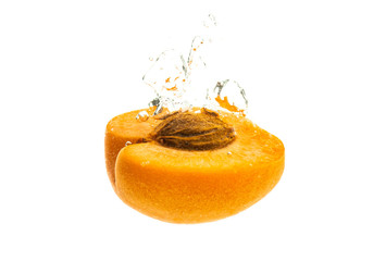 Fresh ripe apricot split in half falling in the clear water
