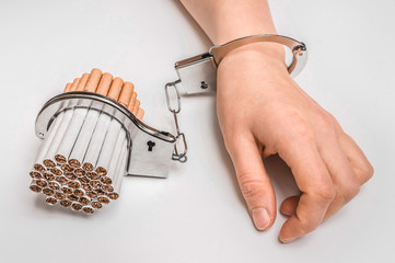 Female hand with handcuffs and cigarettes on white